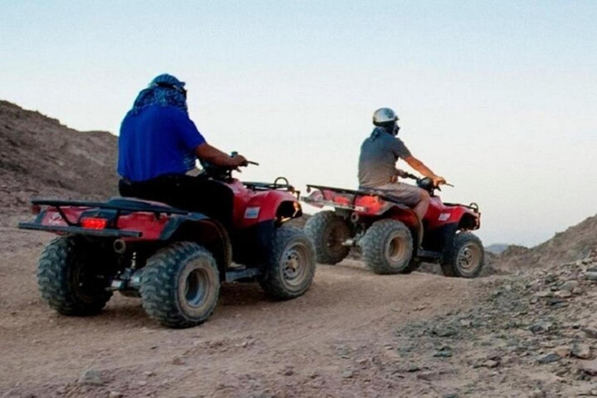 due persone che guidano un quad su una strada sterrata