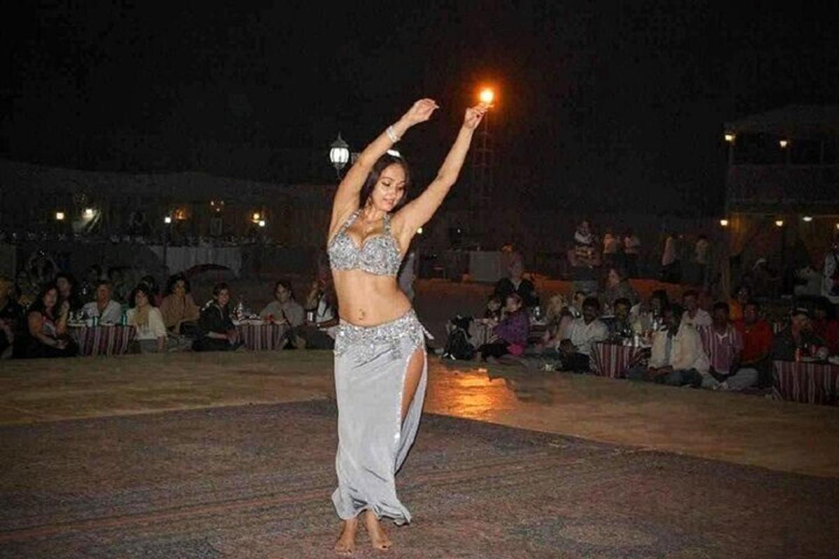 μια γυναίκα που στέκεται σε μια πίστα χορού με τα χέρια της ψηλά