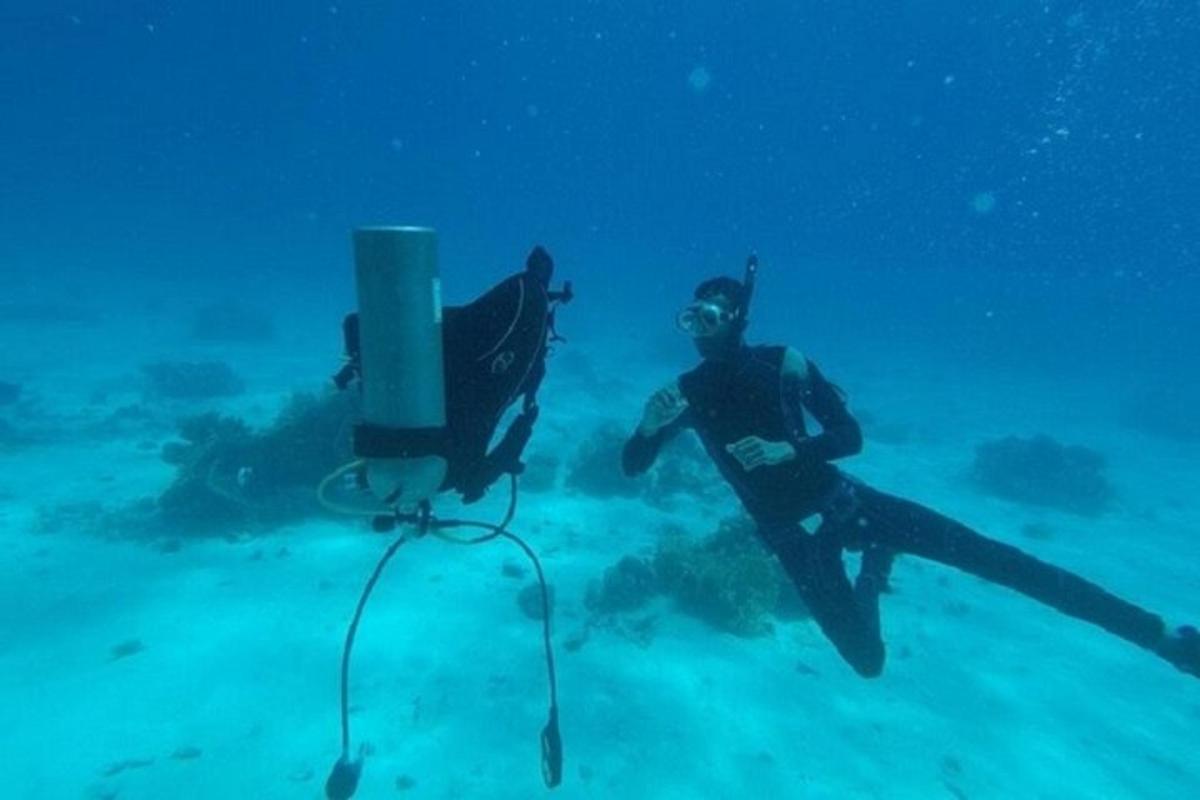 Muž stojí v oceánu vedle potápěčského zařízení