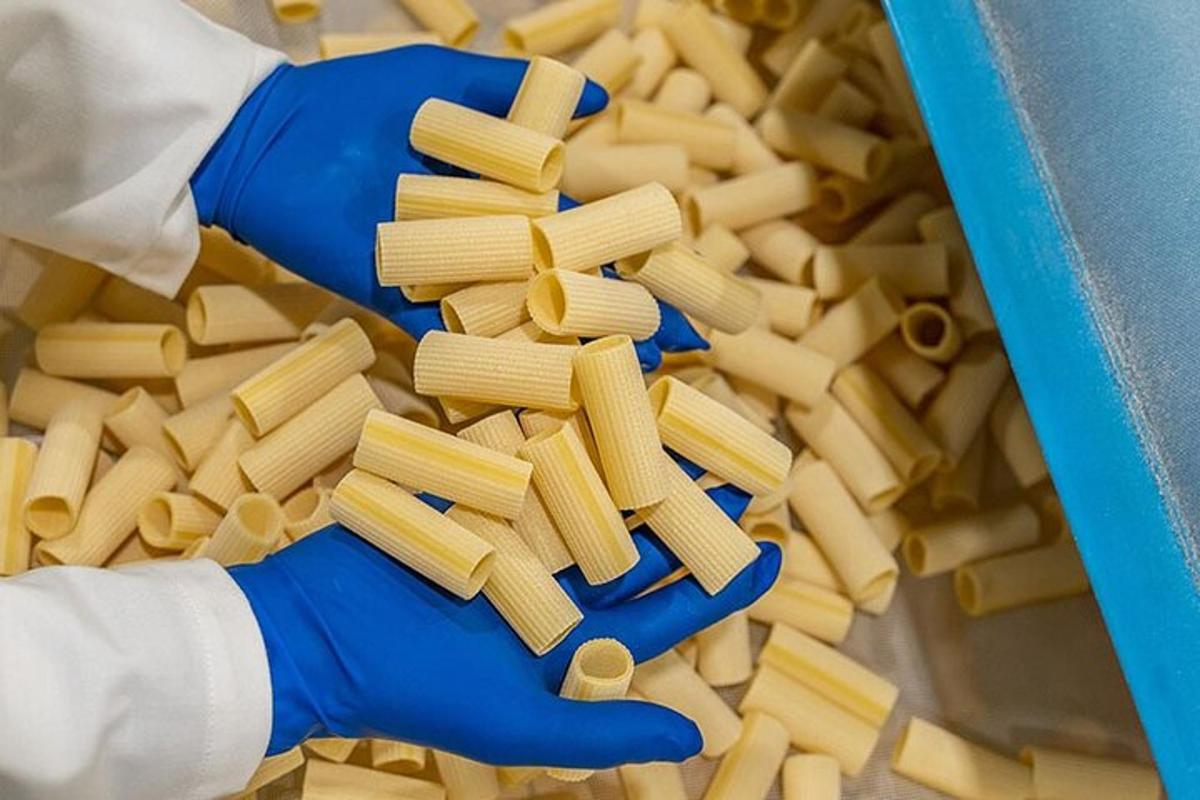 osoba v modrých rukaviciach držiaca tácku s cestovinami