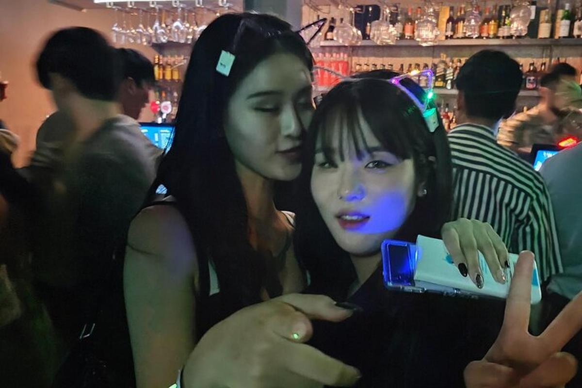 duas garotas olhando para um celular em um bar