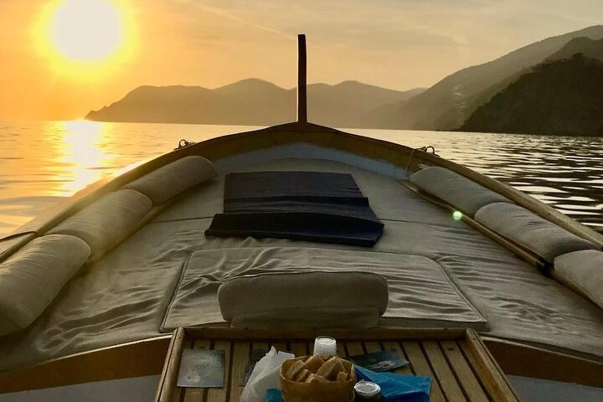 a boat sitting on the water with the sun setting