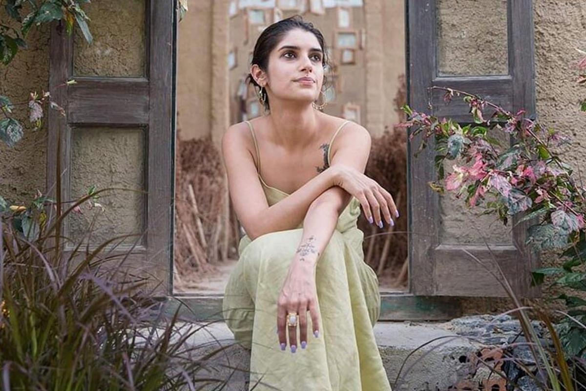Una mujer con un vestido verde sentada frente a una puerta.