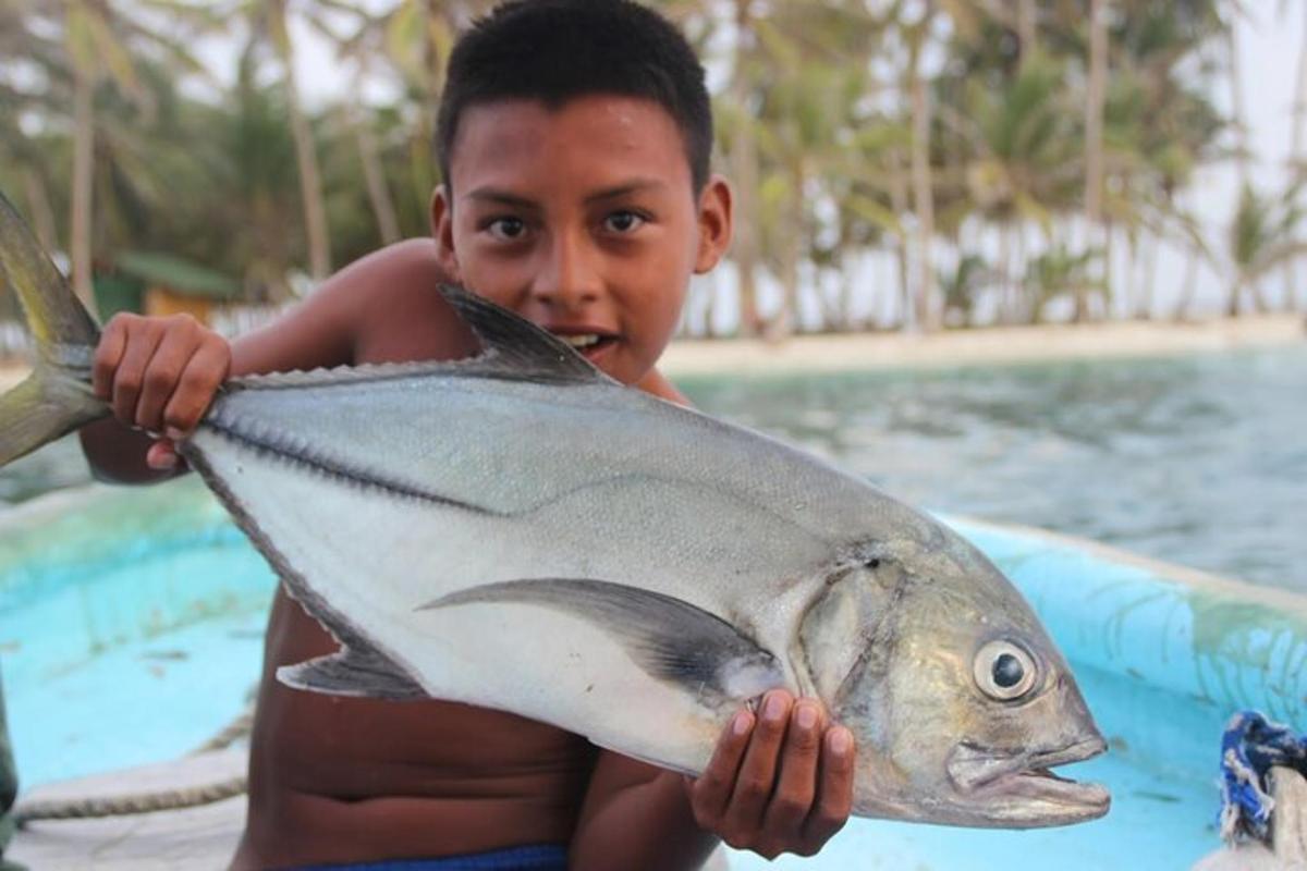 ein Junge, der einen großen Fisch in seinen Händen hält