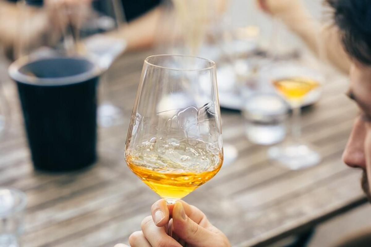 una persona che tiene in mano un bicchiere di vino davanti a un tavolo