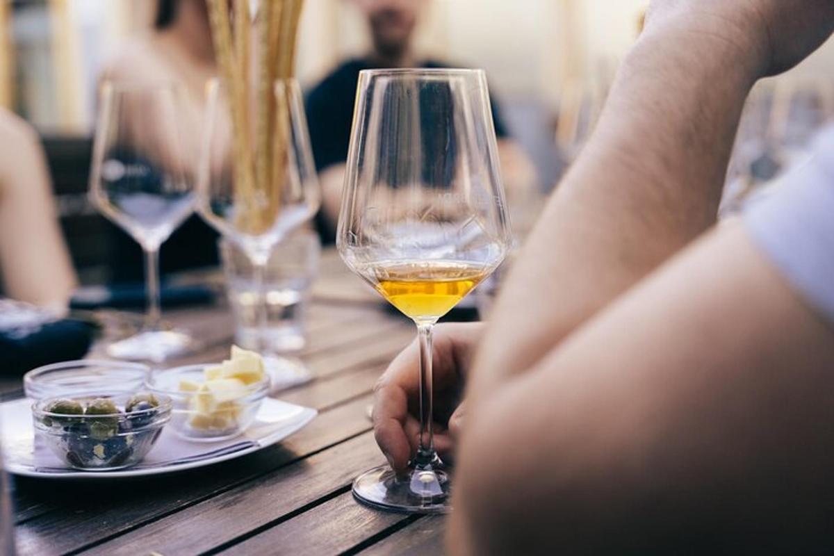 una persona che tiene in mano un bicchiere di vino su un tavolo di legno