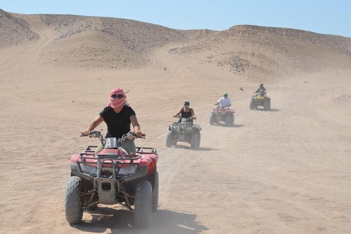 Un grupo de personas viajando en vehículos todo terreno en el desierto.