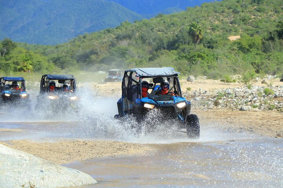 three atvs driving through the water on a dirt road