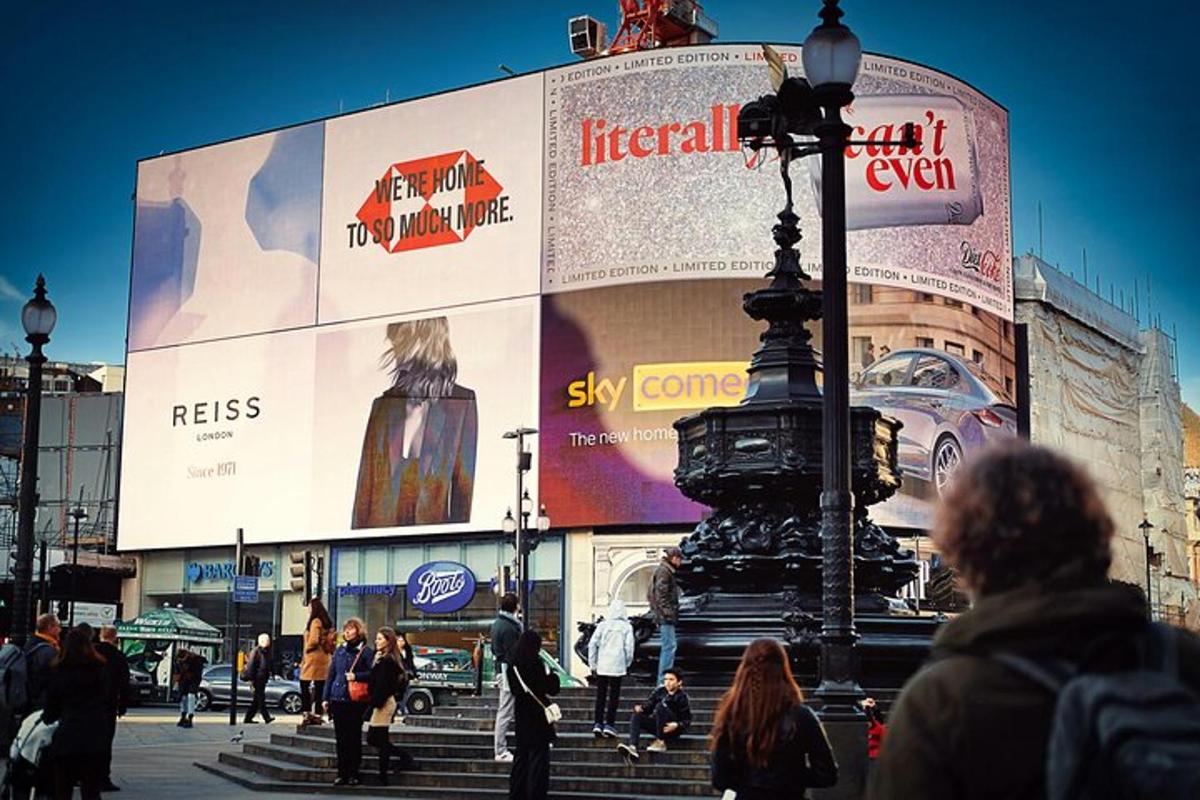 tłum ludzi idący przed dużym billboardem