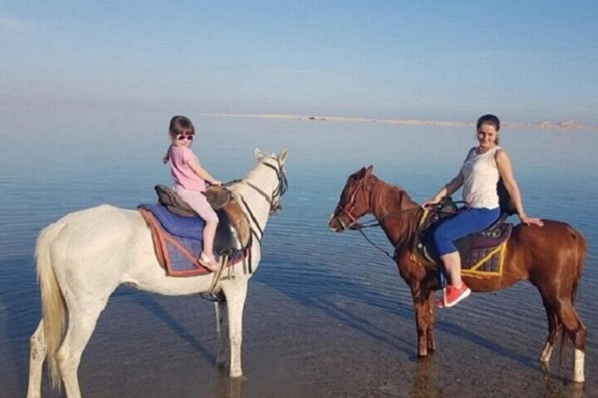egy nő és egy gyermek lovagolnak a tengerparton