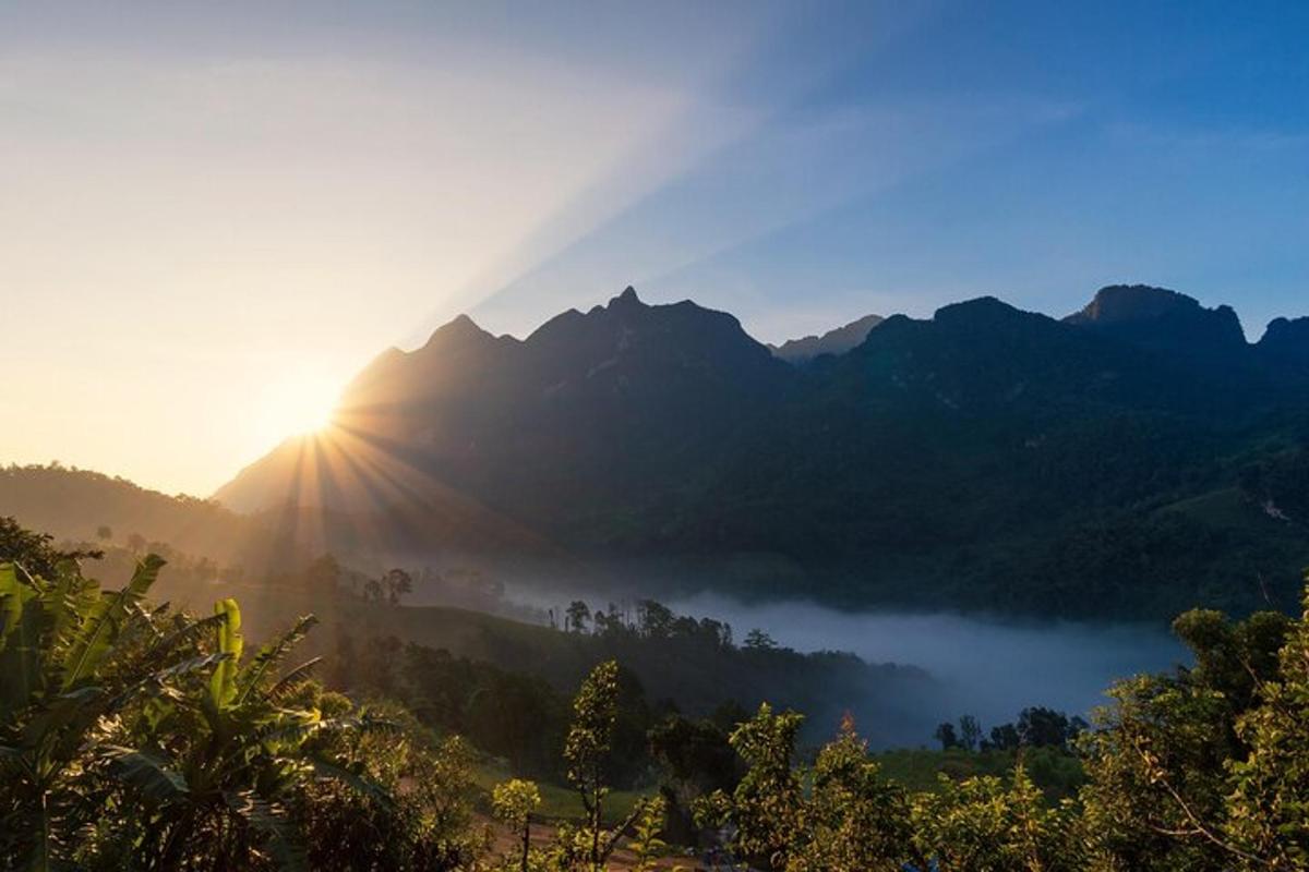 una valle nebbiosa con il sole che splende sulle montagne