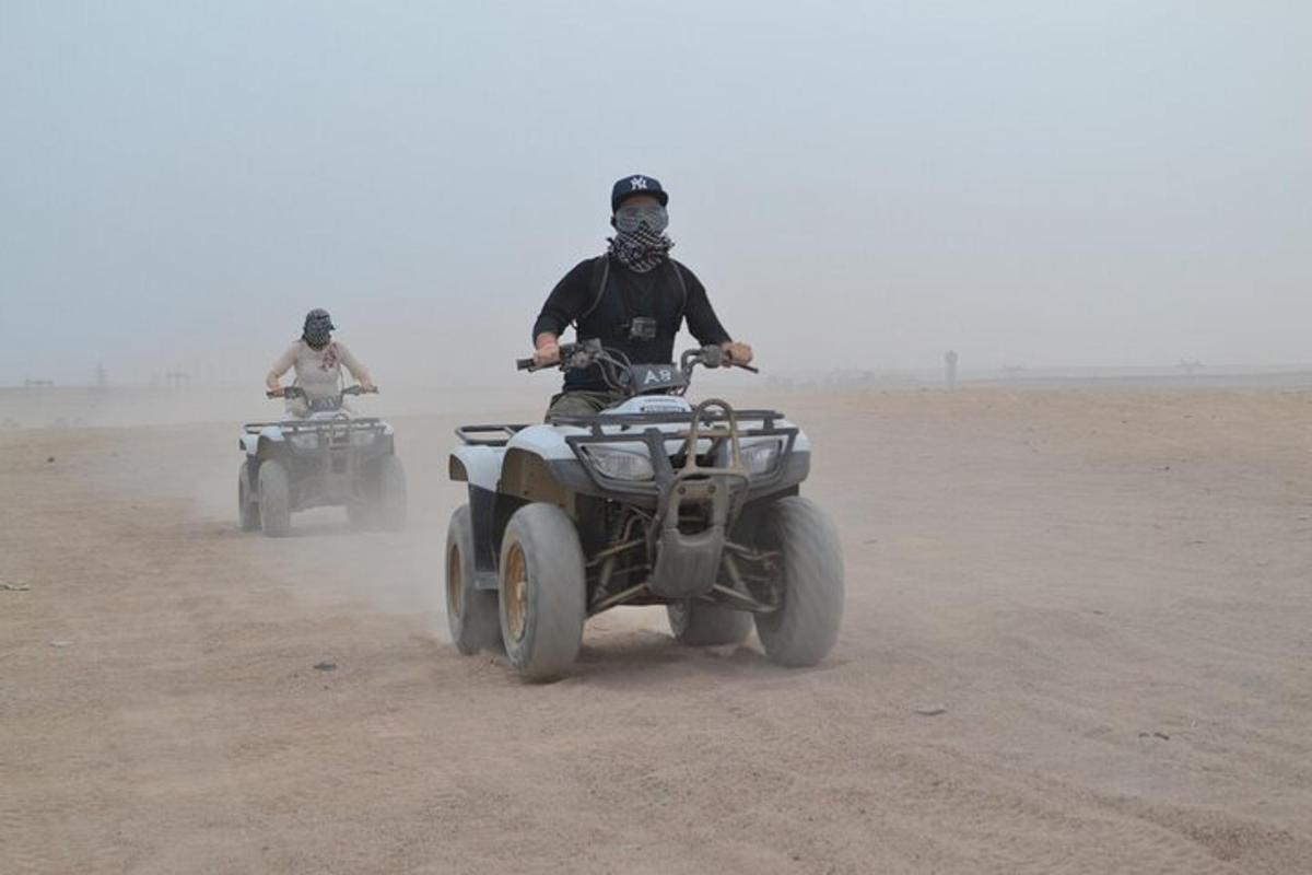 dues persones que condueixen quads al desert