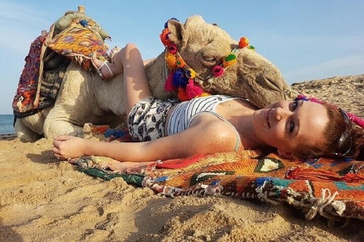 seorang wanita berbaring di pantai dengan teddy bear