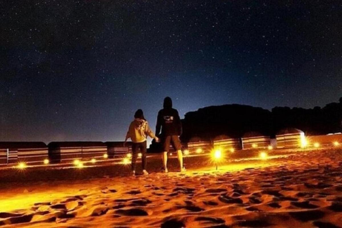 dua orang berdiri di pantai pada waktu malam