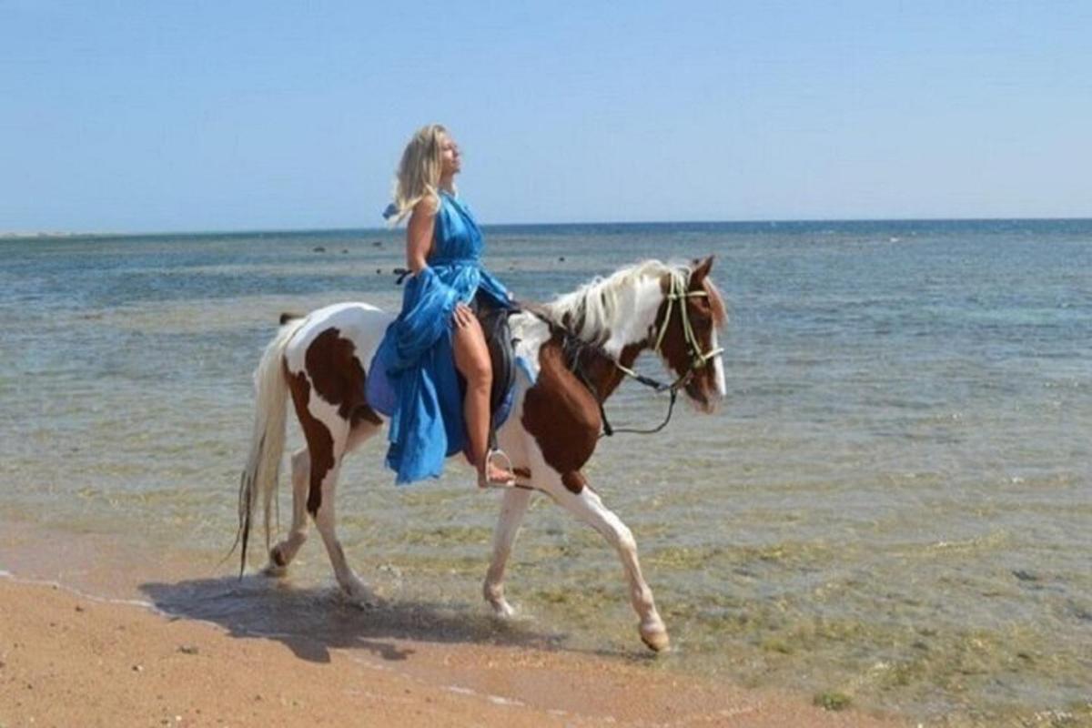 egy kék ruhás nő lovagol a tengerparton