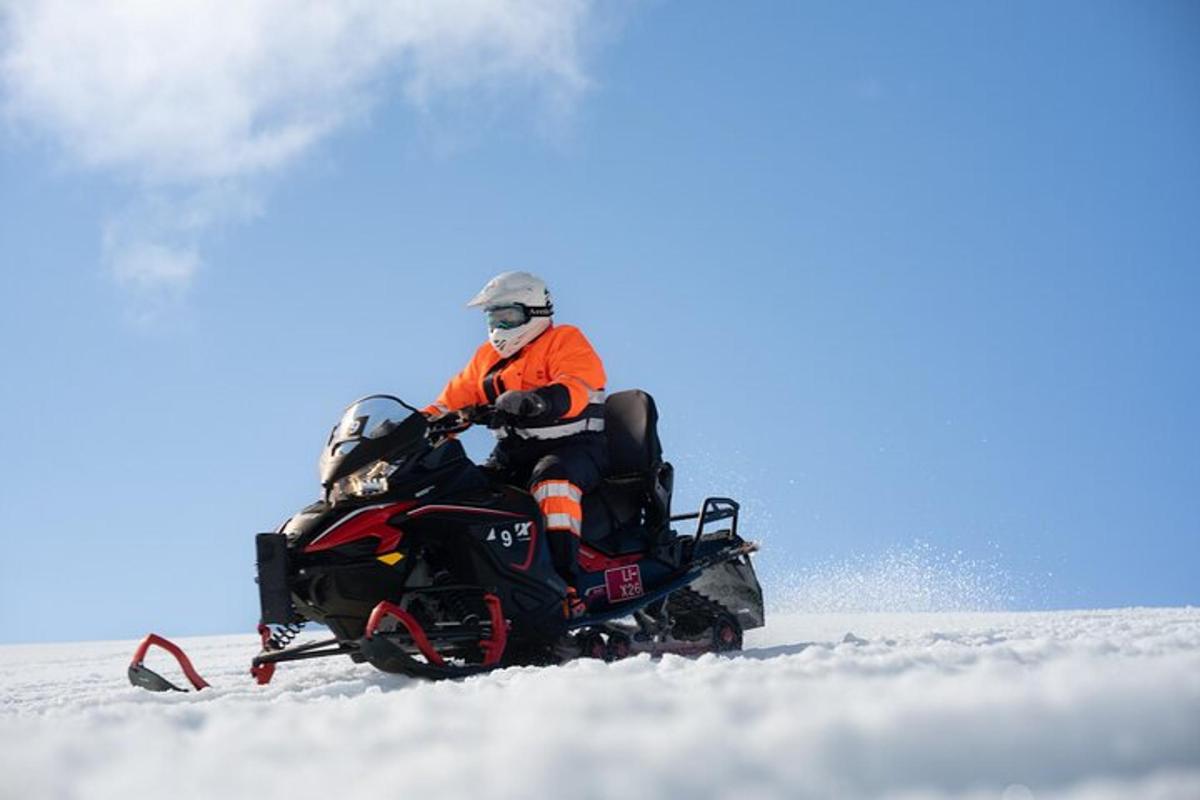 un bărbat care călărește un snowmobil în zăpadă