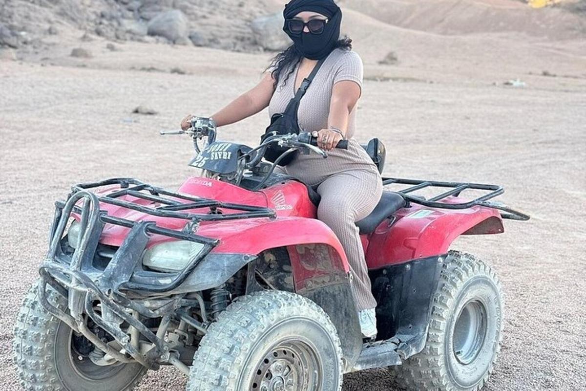 Žena sedí na čtyřkolce v poušti