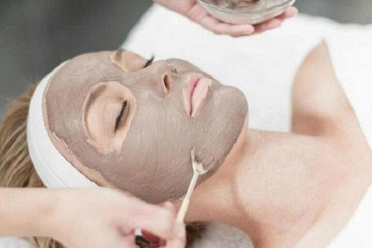 una donna con una mascherina sul viso che si lava i denti