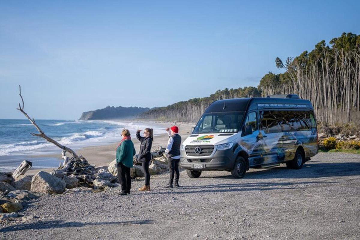 three people standing next to a van parked on the beach