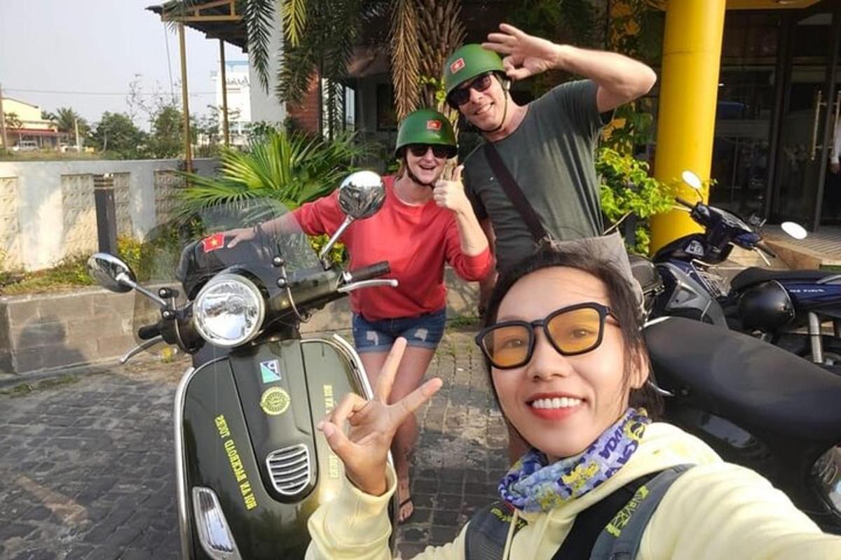 skupina tří lidí stojící vedle motorky