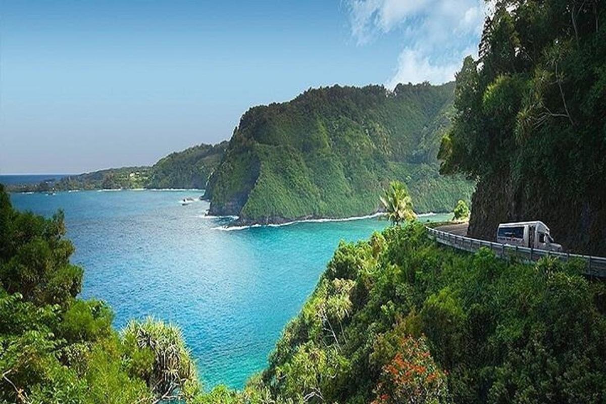 un furgone che guida su una strada accanto a uno specchio d'acqua