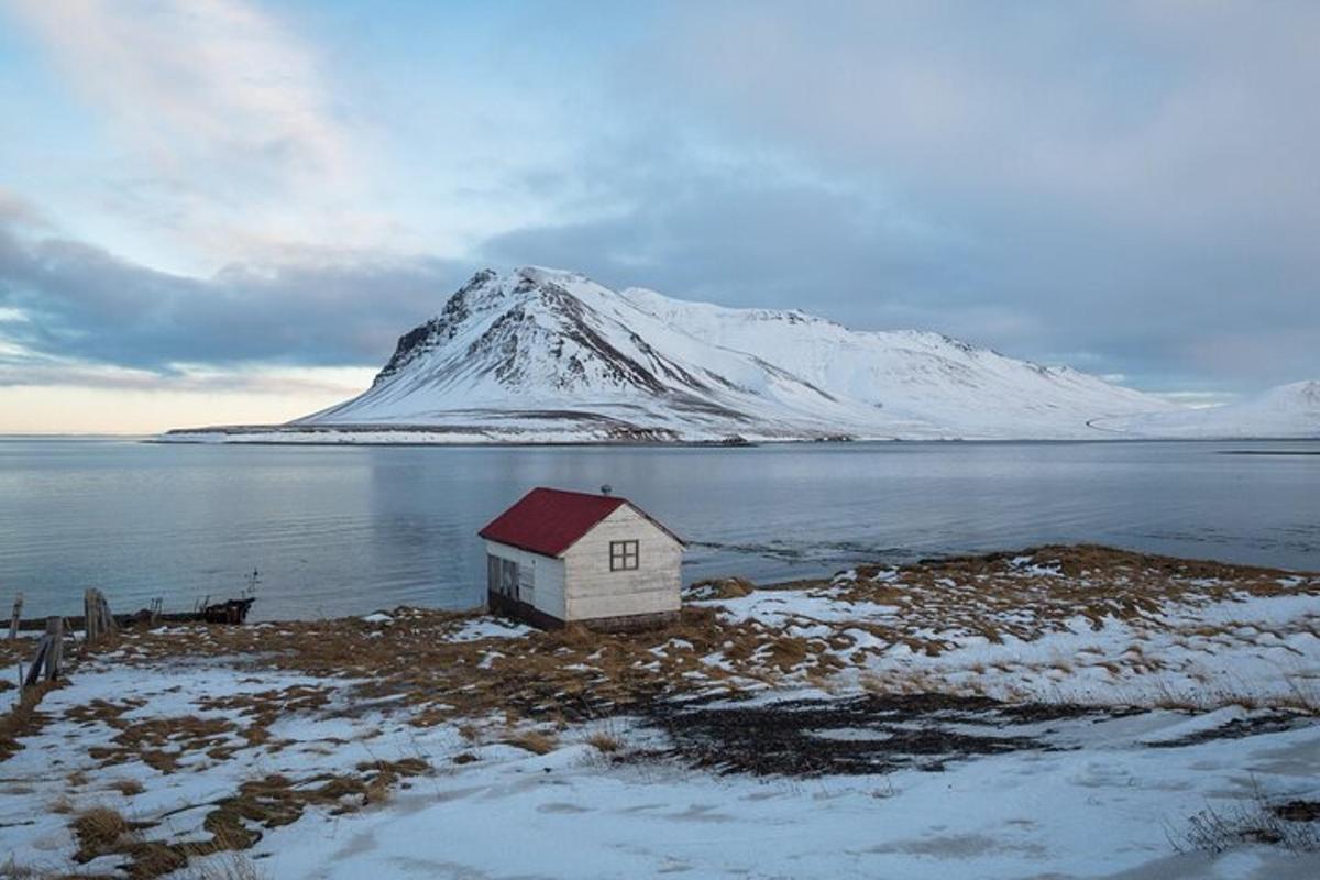 a small house on a island in the water with a mountain