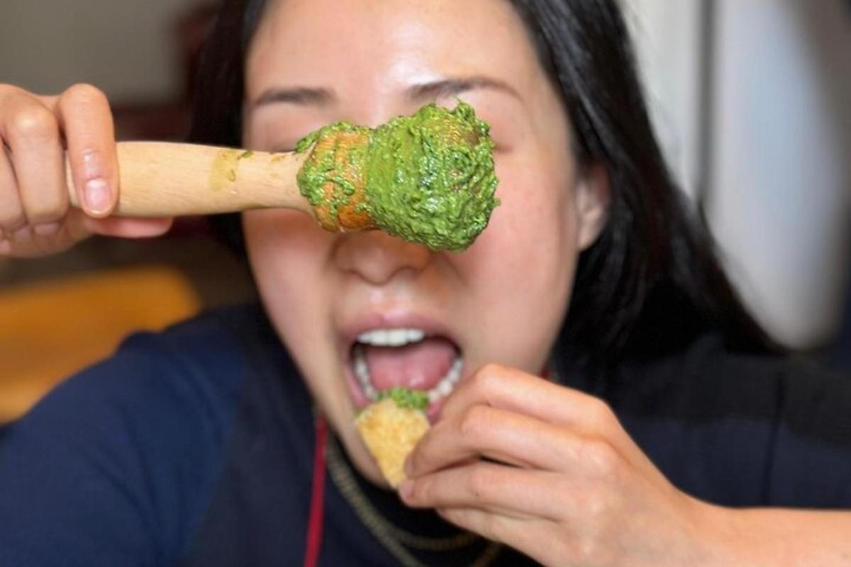 Una mujer comiendo un trozo de brócoli con un palo de madera.
