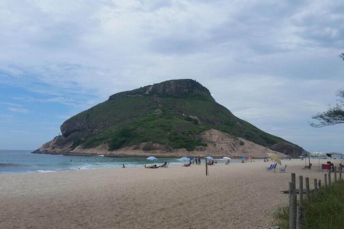 Un grupo de personas en una playa con una montaña.