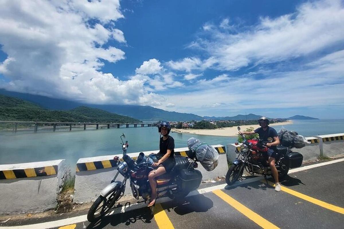 Dos personas viajando en motocicleta por una carretera cerca del agua.