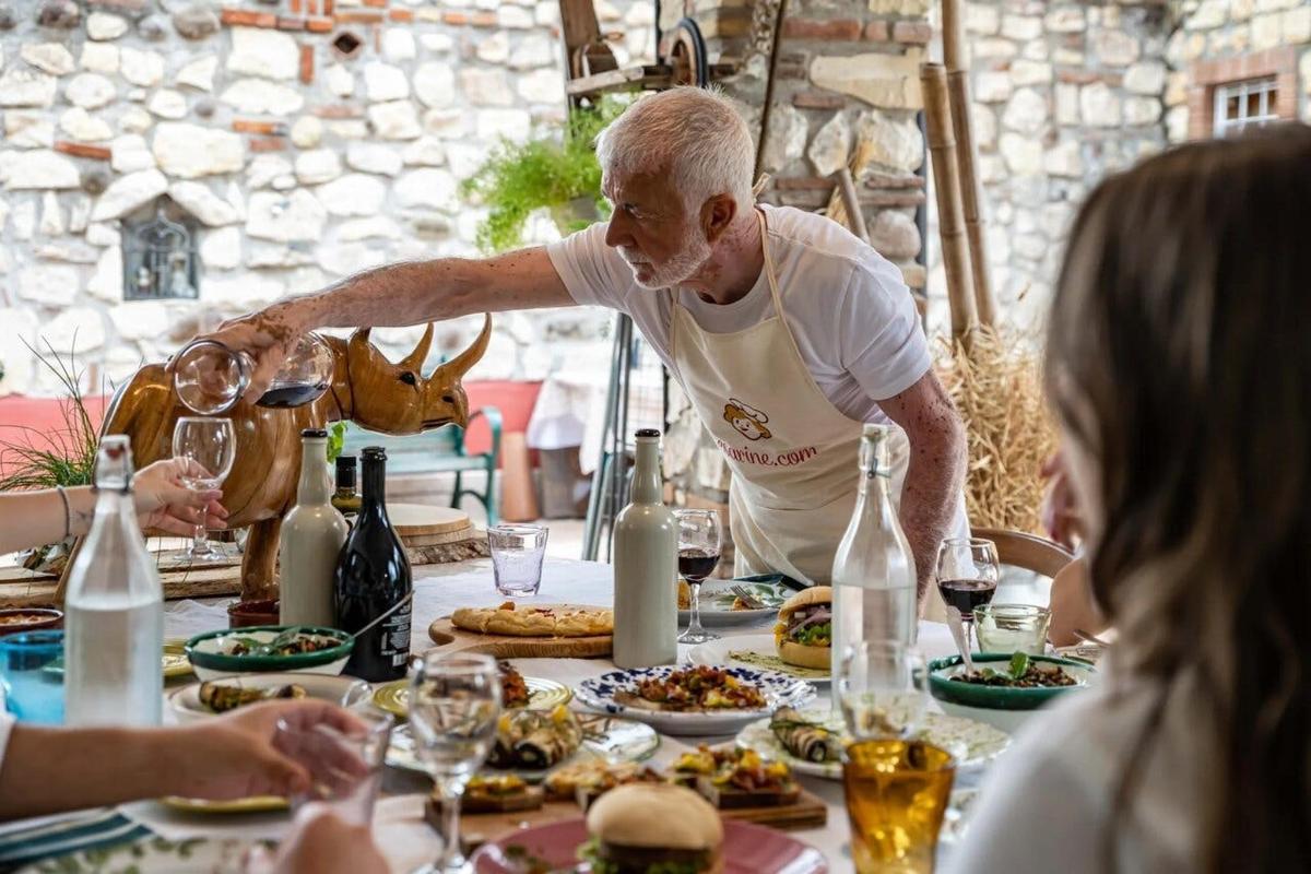 a man pouring wine at a table of food