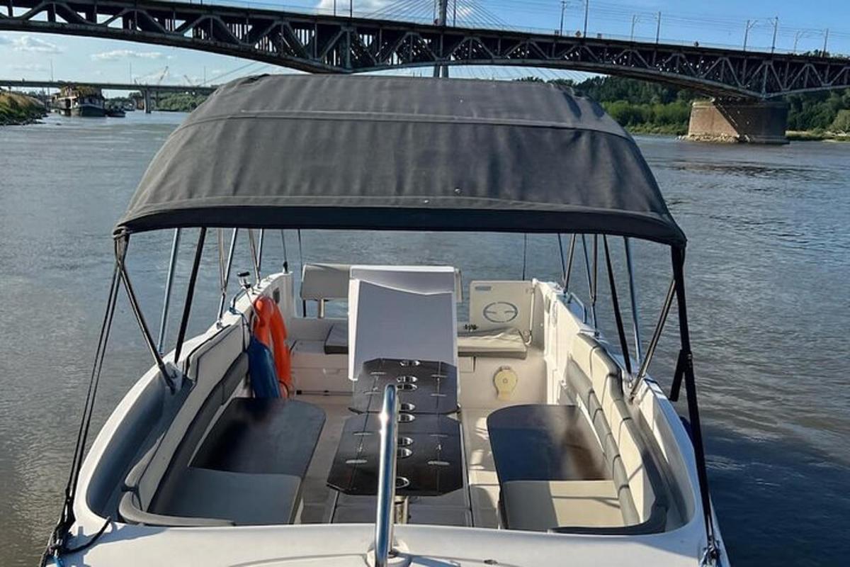 a boat with a cover on the water with a bridge