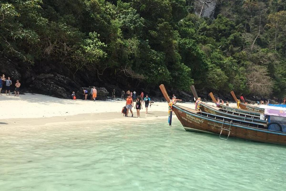 a group of people standing on a beach next to a boat