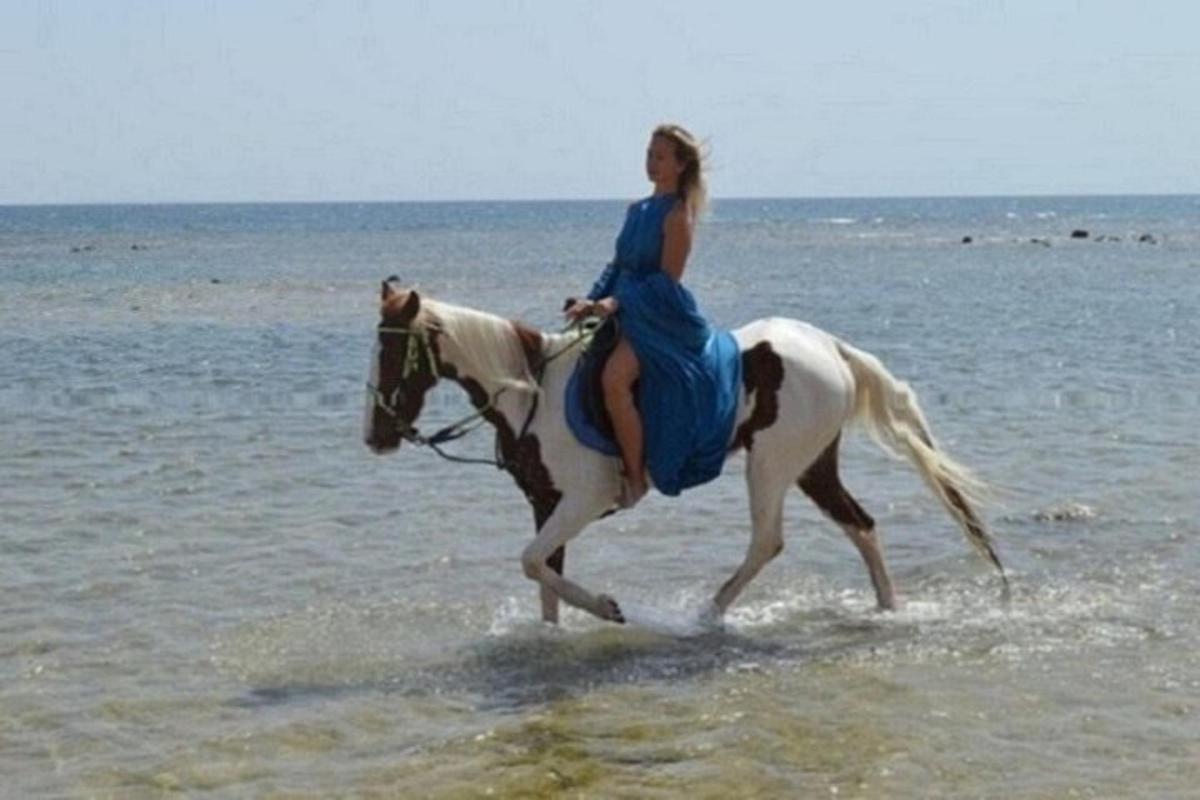 žena jedoucí na koni na pláži