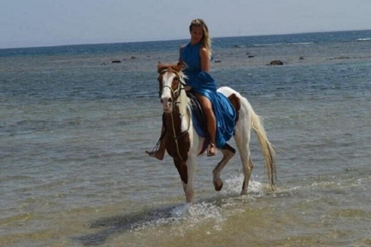 una donna a cavallo sulla spiaggia