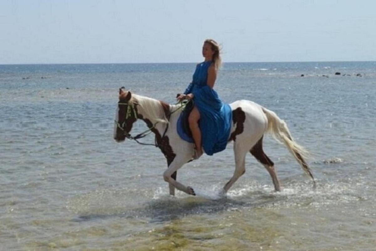 una donna a cavallo sulla spiaggia
