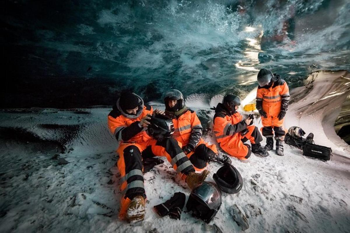 Un grupo de personas con chaquetas naranjas en una cueva de hielo.