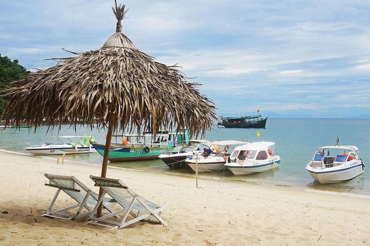 un ombrellone di paglia e sedie su una spiaggia con barche