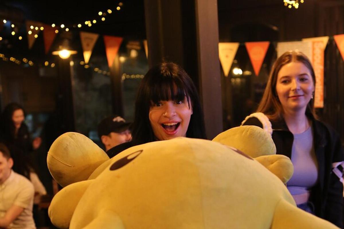 two women standing next to a large teddy bear