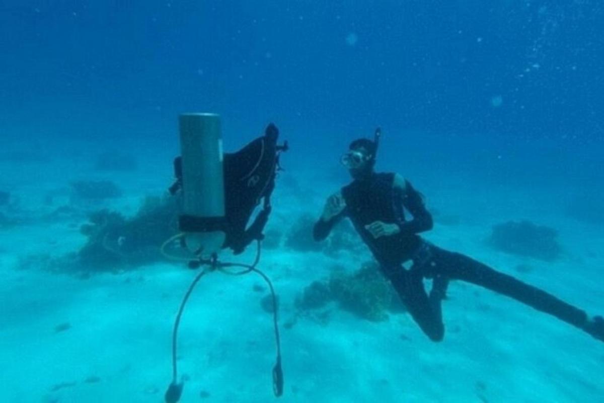 un uomo in acqua accanto a un dispositivo subacqueo