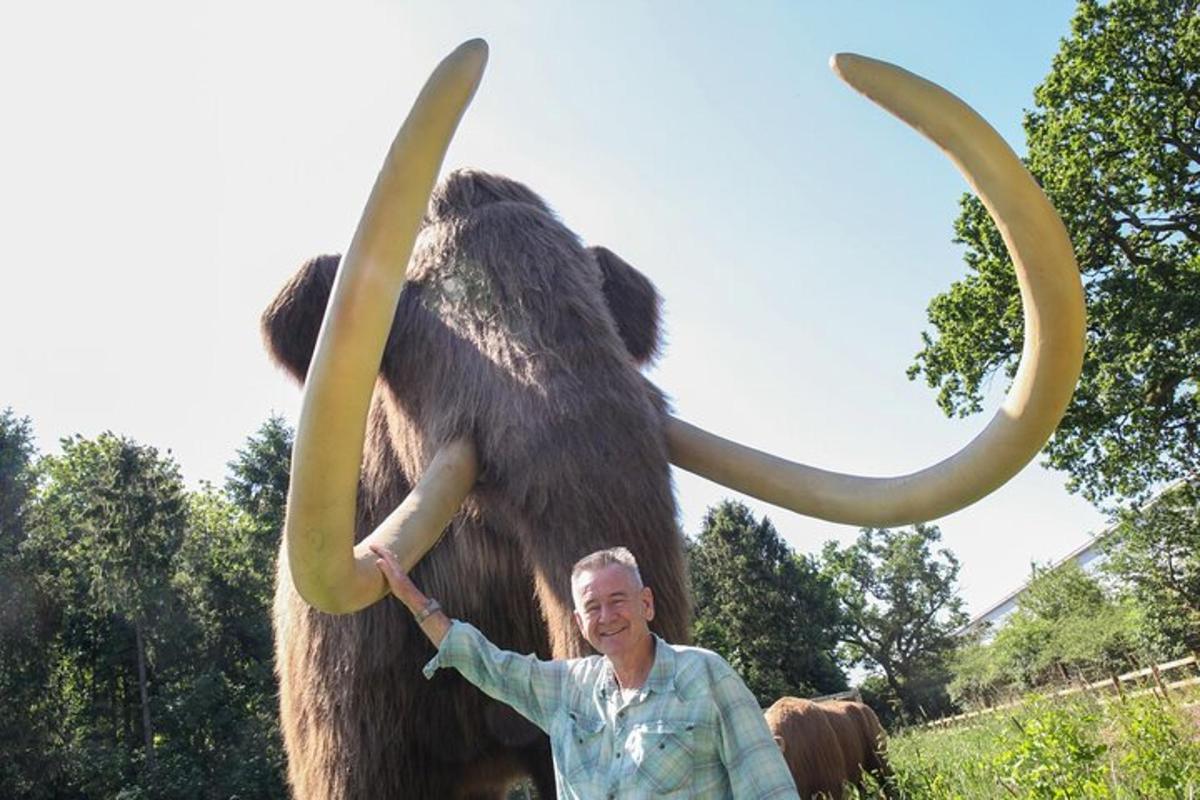 a man standing in front of a statue of a mammoth