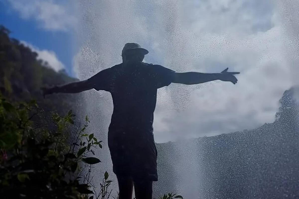 a man standing with his arms out in front of a waterfall