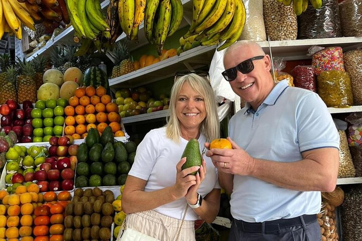 un uomo e una donna in piedi davanti a una bancarella di frutta