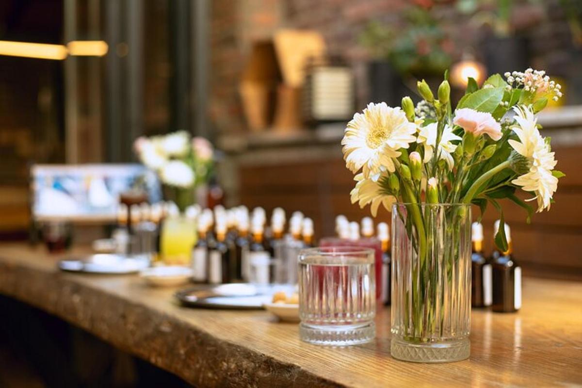 a vase of flowers on a table with wine bottles