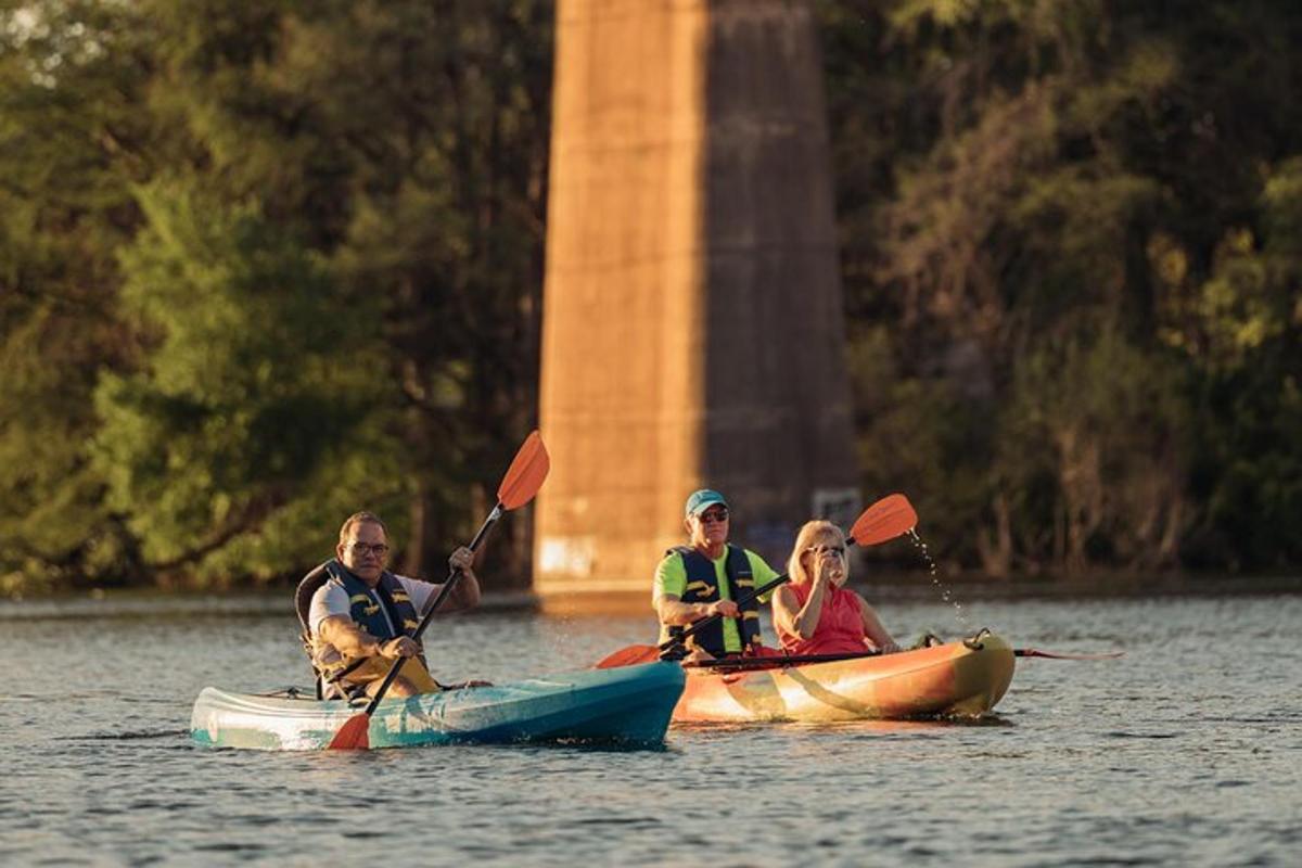 three people in kayaks on the water near a monument