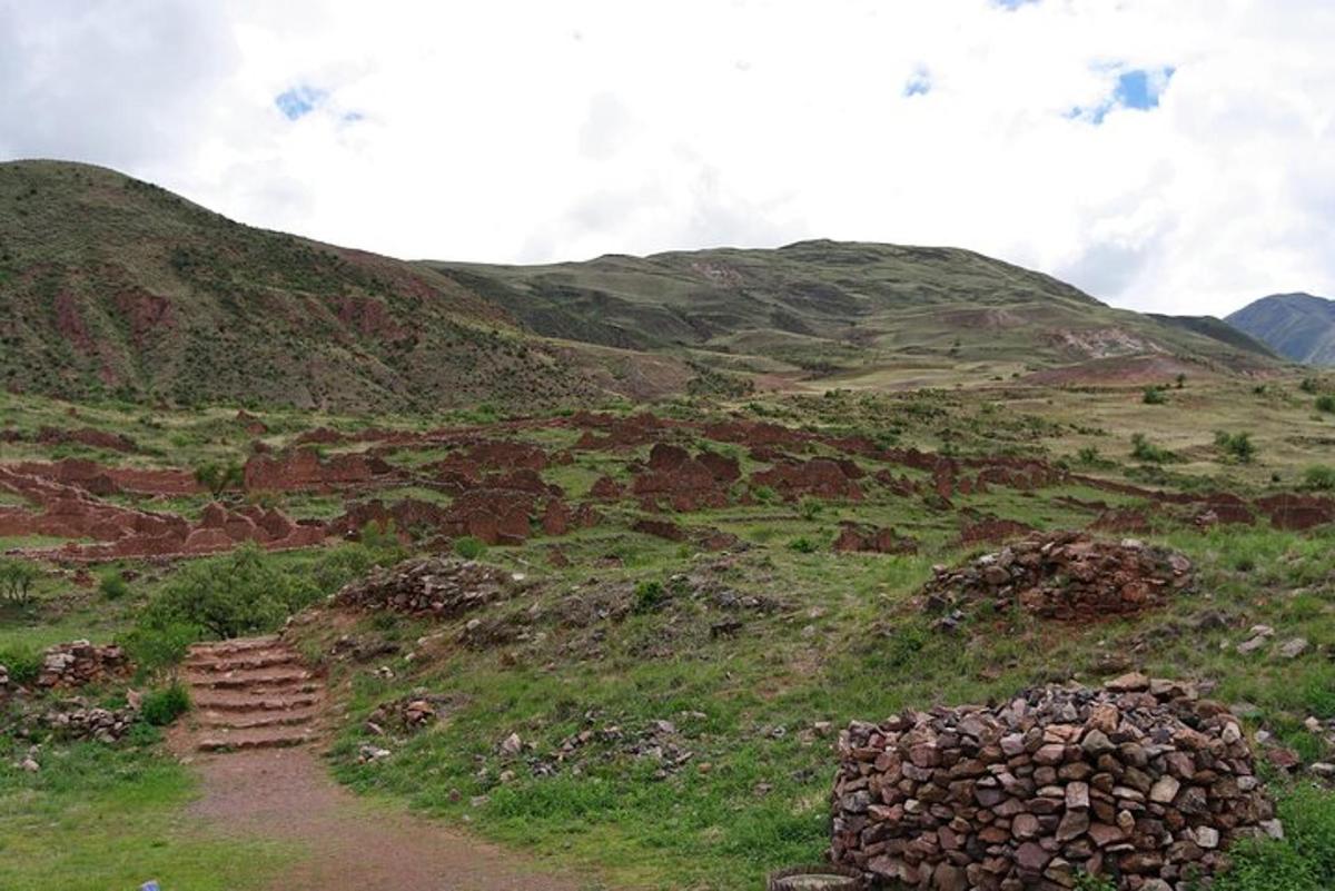 a grassy hill with a path and a pile of rocks