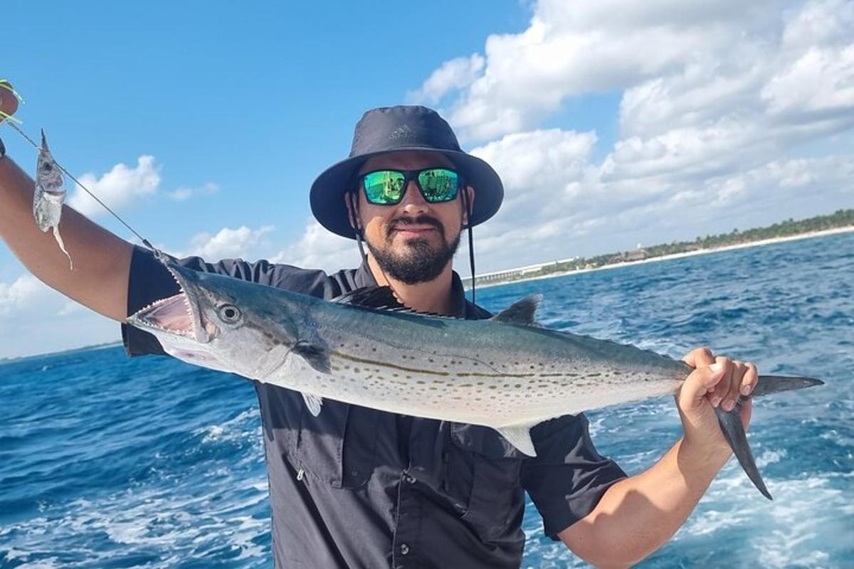 en mann som holder en fisk i havet