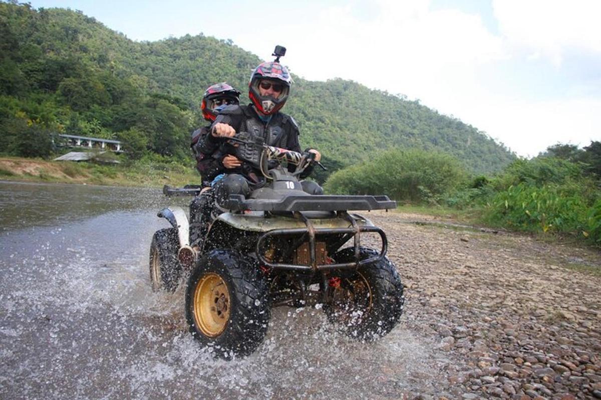 due persone su un veicolo a quattro ruote che attraversano un fiume