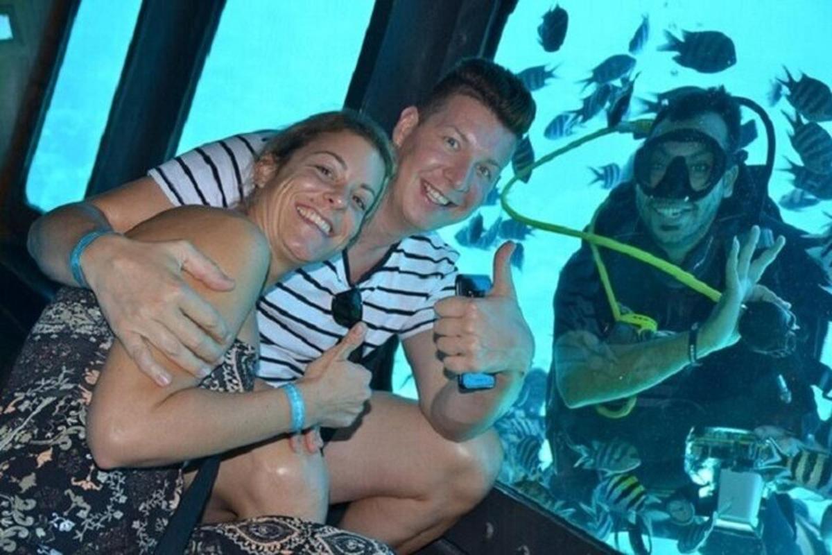 un uomo e una donna che si salutano con il pollice in su davanti a un acquario