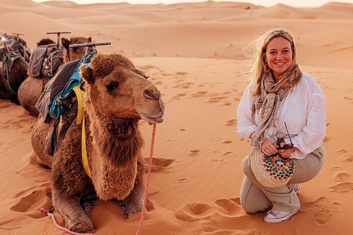 una donna inginocchiata accanto a un cammello nel deserto