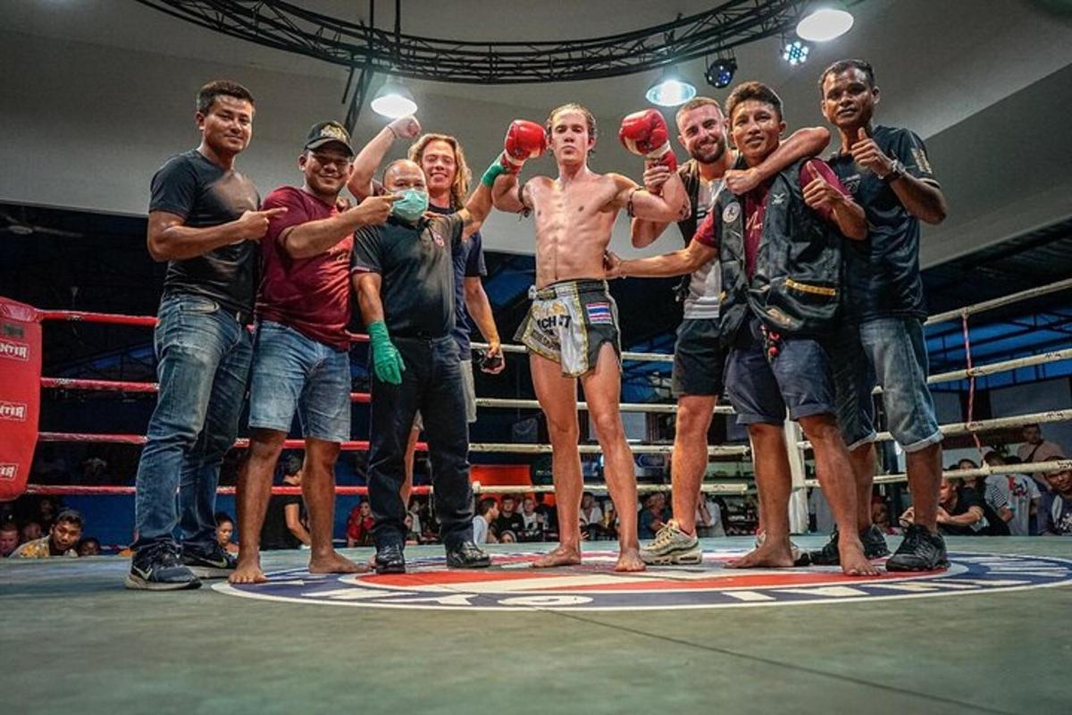 um grupo de pessoas em pé em frente a um ringue de boxe